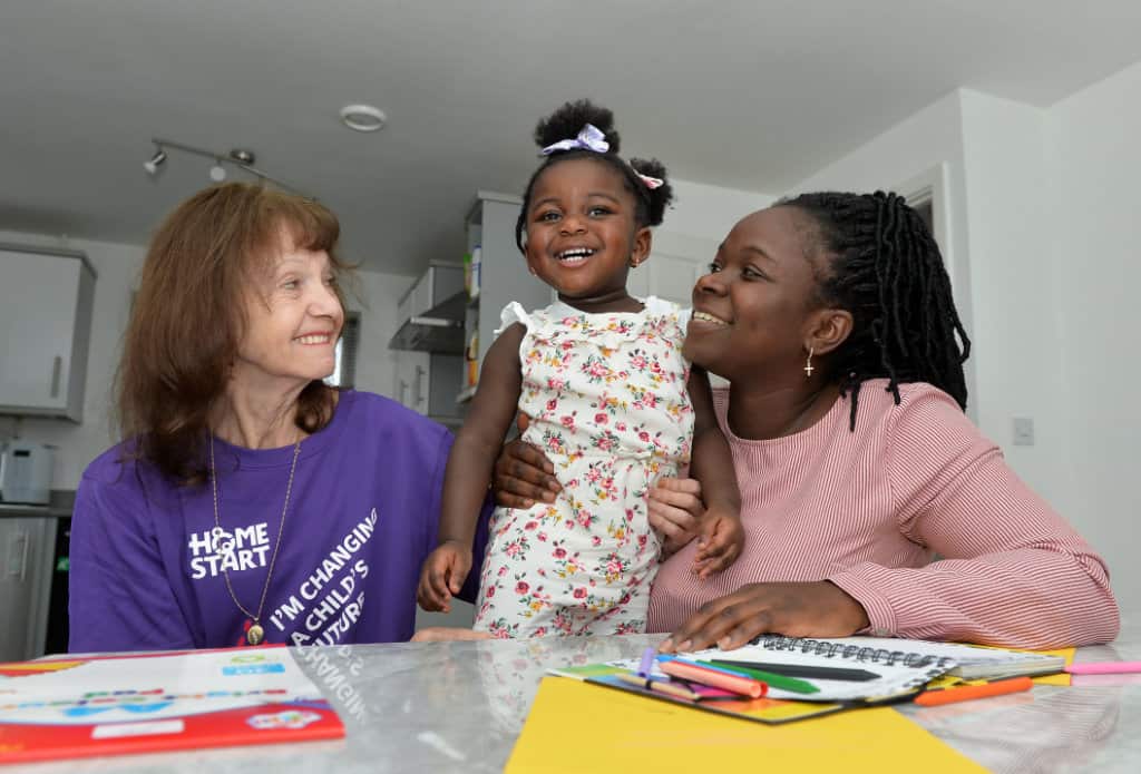 Image of Home-Start volunteer at table with mum and child.