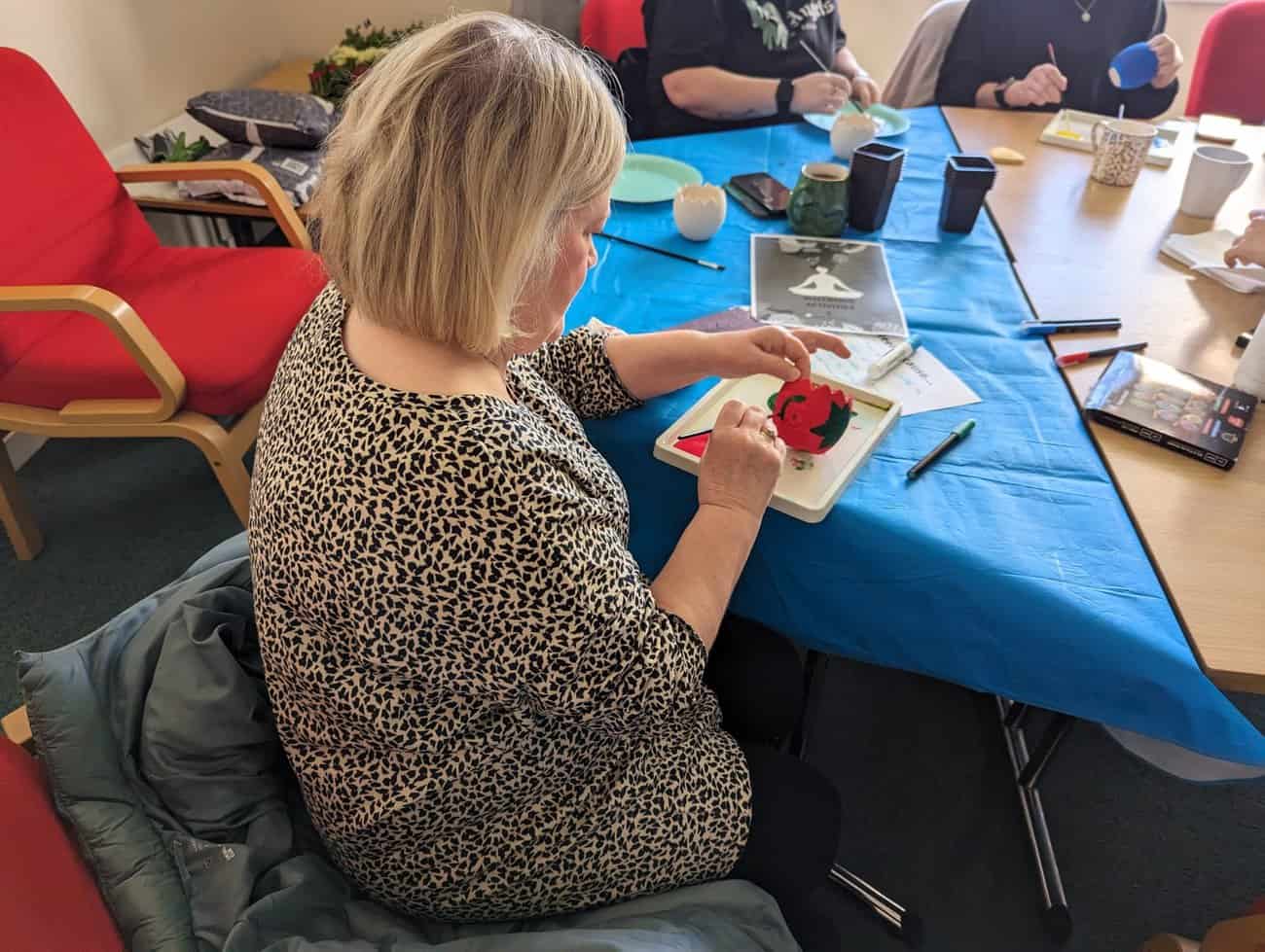 Image of a Home-Start Volunteer painting a plant pot. 
