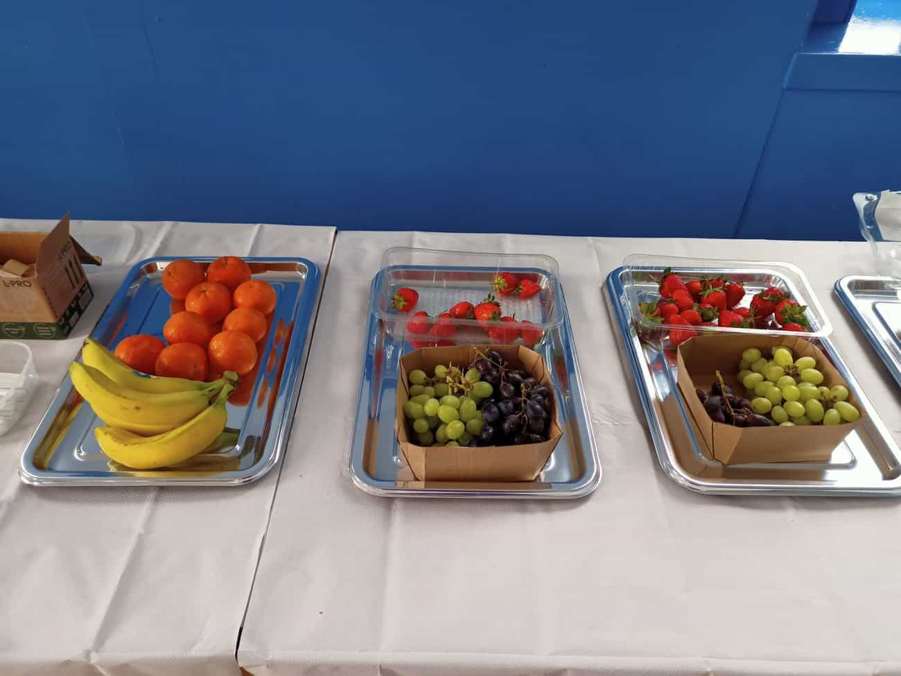 Image of platters with fresh fruit, bananas, oranges, grapes and strawberries.