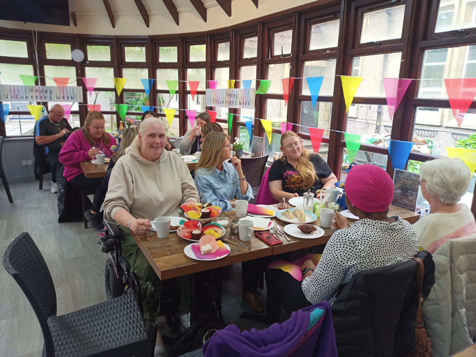 Image of volunteers sat at table in cafe enjoying an Afternoon tea celebrating Volunteers Week