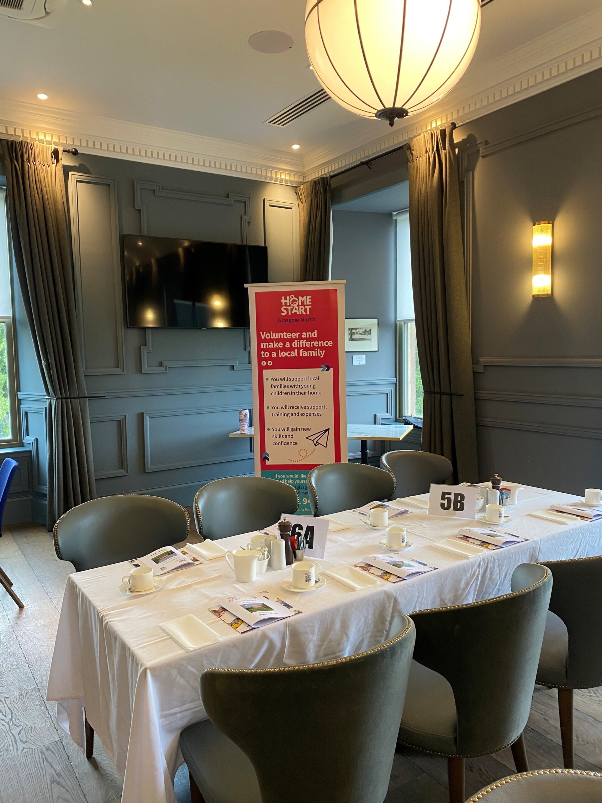 Image of table at Glasgow Golf Club set up for meal at the ProAm event. There is a Home-Start pop up banner in the background.