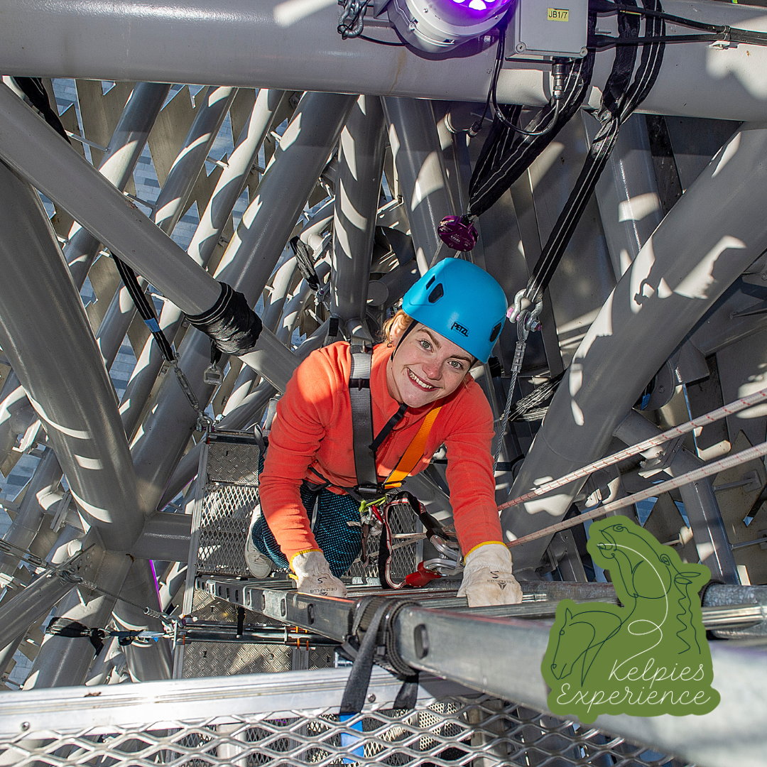 Image of someone climbing up inside the Kelpies. They are looking up smiling at the camera.