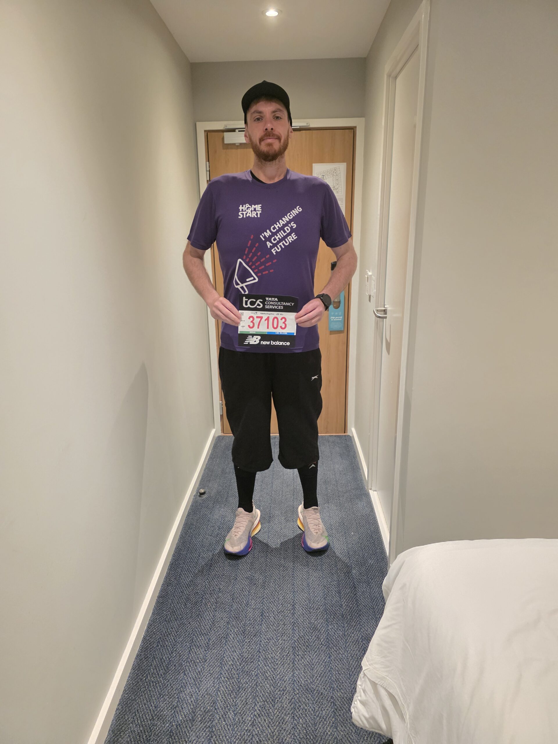 Lewis standing with this London marathon number and purple Home-Start t-shirt.