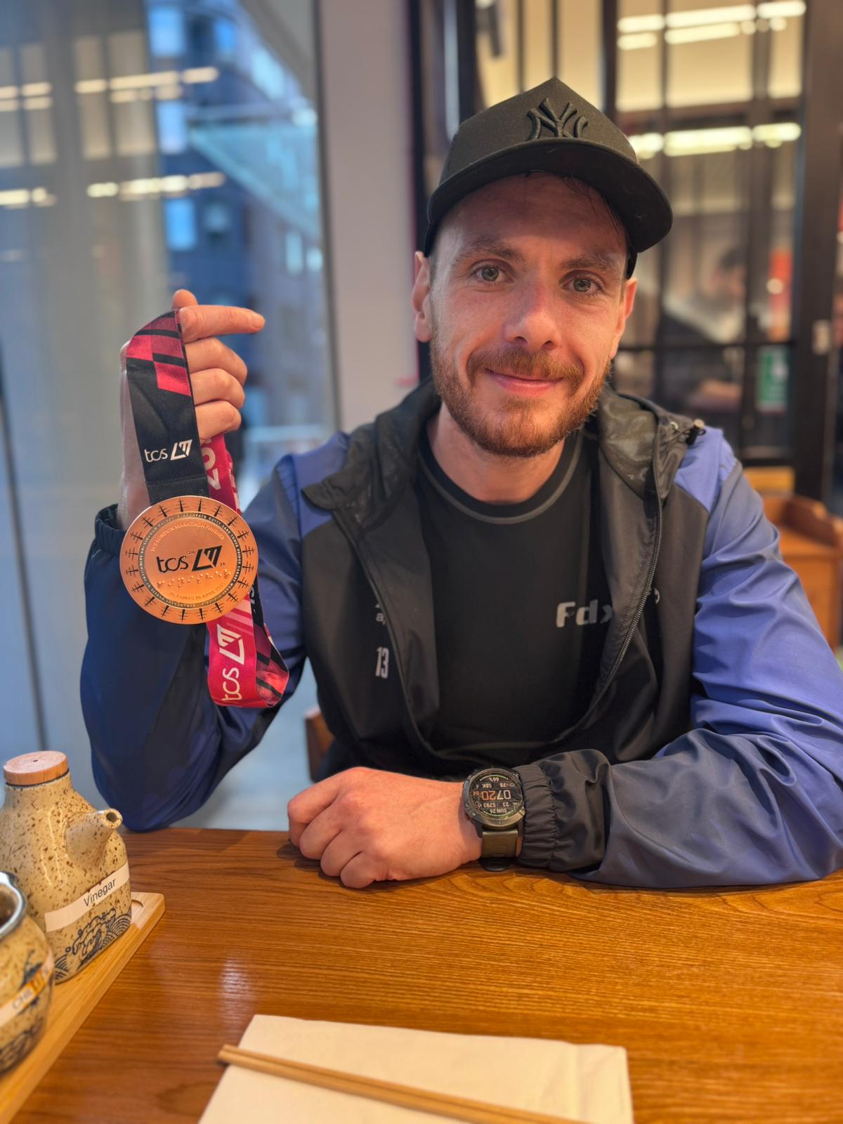 Image of Lewis , aka Tiny with his 2026 London Marathon medal sitting at the table.