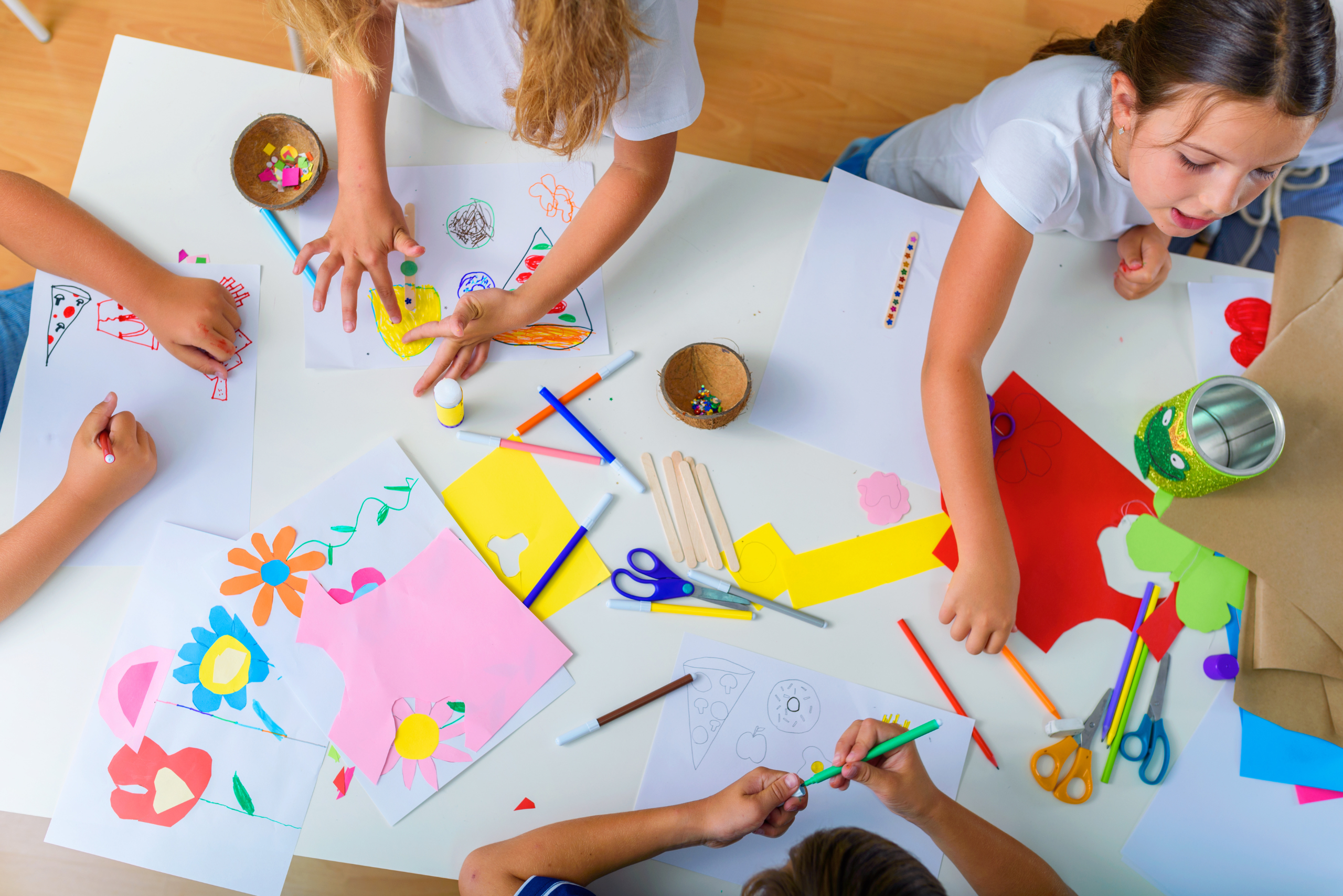 Image of children at a table doing arts and crafts using card and finger painting. 