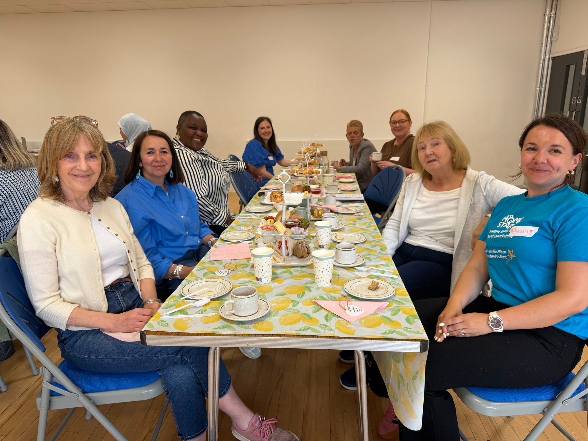 Image of volunteers with staff sitting at a table eating an afternoon tea.