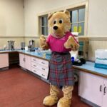 Image of Slanj the Bear giving a thumbs in his Home-Start tartan kilt.