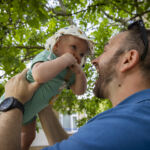 Image of dad lifting up smiling baby